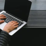 Tangan mengetik di laptop untuk pendaftaran usaha secara online